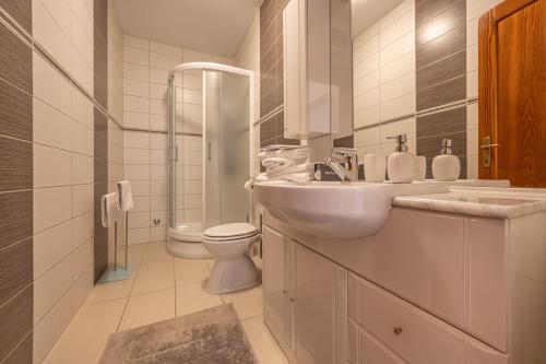 a white bathroom with a sink and a toilet at Apartments Villa Residenca in Novi Vinodolski