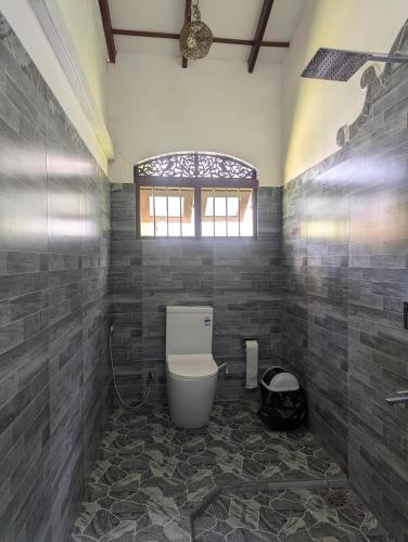 a bathroom with a toilet and a window at Sea Turtles Bungalow in Induruwa