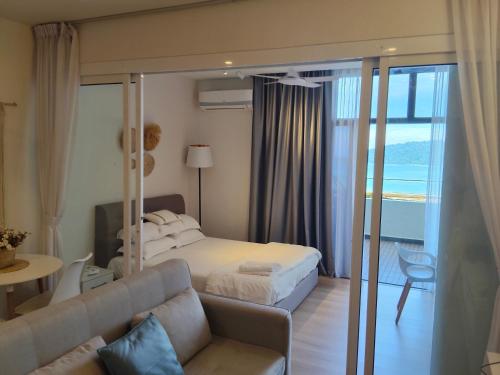 a bedroom with a bed and a couch and a table at The Shore KK - Seaview Suite with Stunning Sunset & Private Balcony in City Centre in Kota Kinabalu