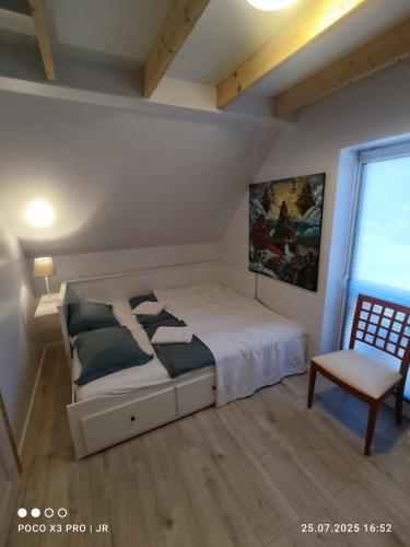 Un dormitorio con una cama y una silla y una ventana. en Baltic Rafa, en Niechorze