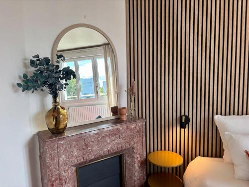 a fireplace with a mirror and a vase on it at Les Cocons d'Agathe, La Marinière, la plage à pieds in Larmor-Plage