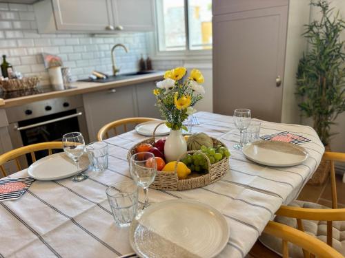 a table with a basket of fruit and a vase of flowers at Les Cocons d'Agathe, La Marinière, la plage à pieds in Larmor-Plage
