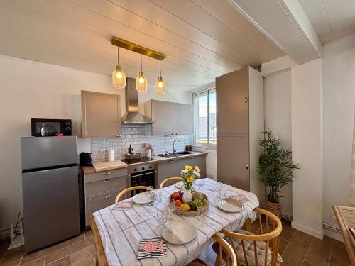 a kitchen with a table with a bowl of fruit on it at Les Cocons d'Agathe, La Marinière, la plage à pieds in Larmor-Plage