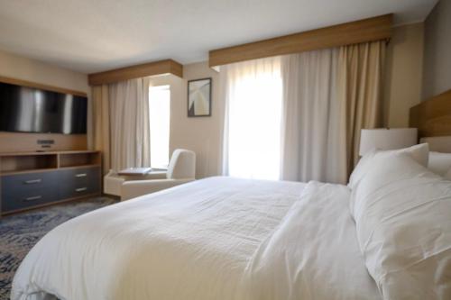 a hotel room with a white bed and a television at Beachwood Extended Suites in Beachwood