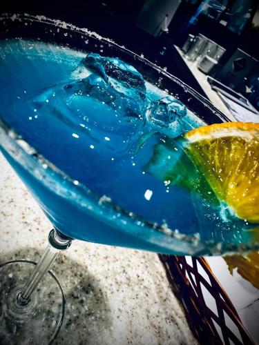 a blue drink in a glass with an orange slice at Hotel Sobieszewo in Gdańsk