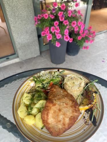 a plate of food with a piece of fish and vegetables at Hotel Sobieszewo in Gdańsk
