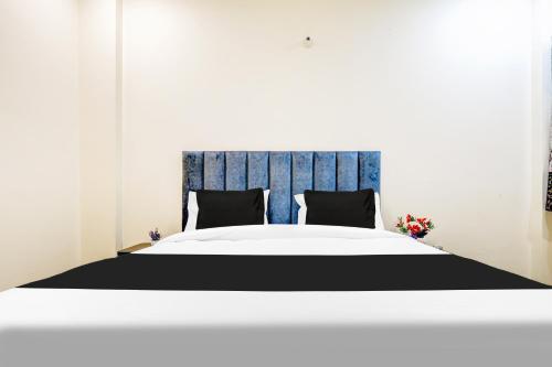 a bed with a blue headboard and two pillows at Hotel O YUVI in New Delhi