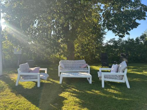 four white chairs sitting in the grass under a tree at Solberg Inn 