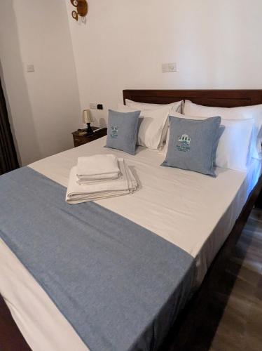 a large bed with blue and white sheets and pillows at Sea Turtles Bungalow in Induruwa