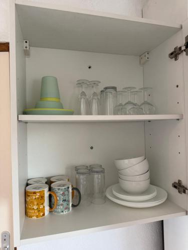 a cupboard filled with dishes and other items at L'Alcôve Alsacienne avec climatisation et terrasse in Entzheim