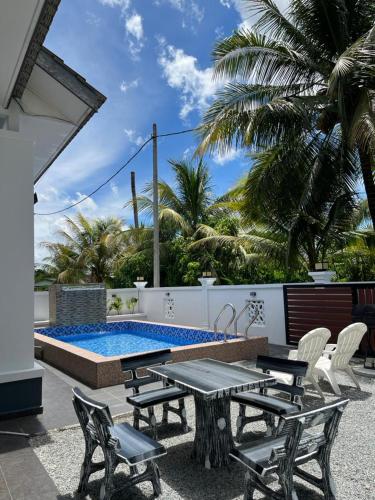 a patio with a table and chairs and a pool at Senjaloka Homestay SWIMMING POOL in Bachok