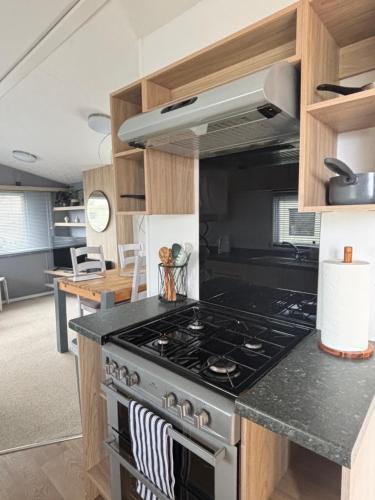a kitchen with a stove top oven in a room at Padstow Holiday Base Bright Two Bedroom Lodge at Seven Bays in St Merryn