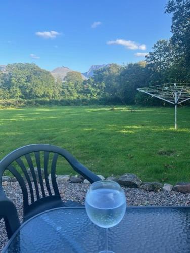 a glass of wine sitting on a table with a field at Hawthorn Lodge in Fort William