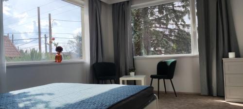 a bedroom with a bed and two chairs and a window at Mediterran Garden Lil Apartment in Vecsés