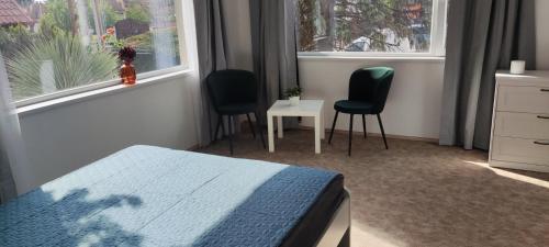 a bedroom with two chairs and a bed and two windows at Mediterran Garden Lil Apartment in Vecsés