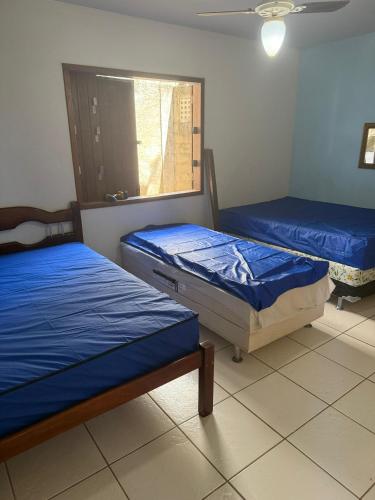 two beds sitting in a room with a window at Casa de Temporada Meaipe in Guarapari