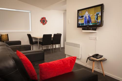 a waiting room with a couch and a tv on the wall at 538 Great King Motel in Dunedin