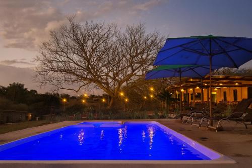 a blue pool with an umbrella next to a house at Pousada Rio Gouveia in Brotas