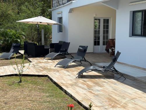a patio with four chairs and an umbrella at ALLAMANDA DES BOIS in Deshaies
