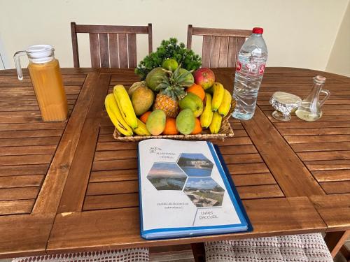 a basket of fruit on a table with a book at ALLAMANDA DES BOIS in Deshaies