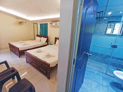 two beds in a room with a shower and a bathroom at Golden dreams in Gokarna