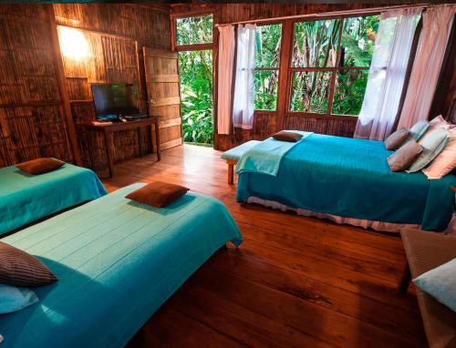 a room with two beds and a television in a cabin at El Septimo Paraiso in Mindo