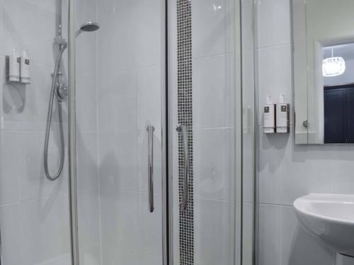 a white bathroom with a shower and a sink at Dunlin Haven in Sandside