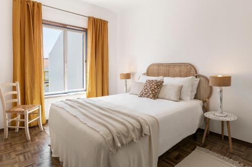 a bedroom with a white bed with a large window at Casa da Lua in Ericeira