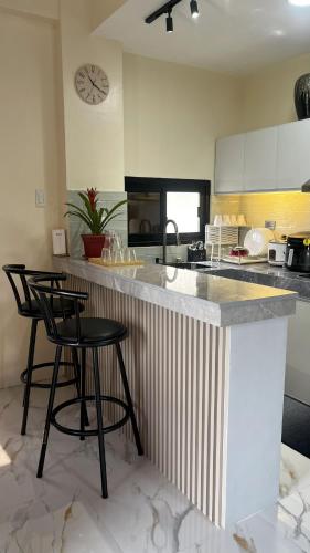 une cuisine avec un comptoir et deux tabourets de bar dans l'établissement ZMZ Silang Transient House near Tagaytay, à Silang