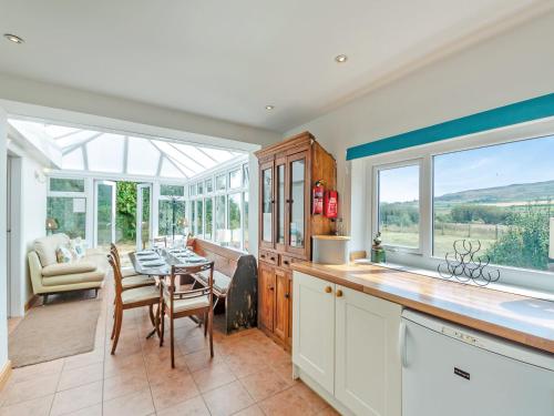 a kitchen with a table and a dining room at Brynawel in Bryncroes