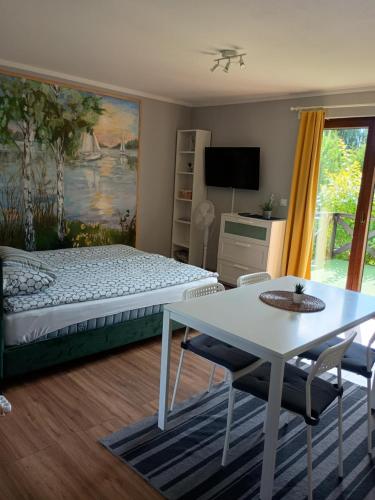 a bedroom with a bed and a table and a desk at Mazurska Apartamenty in Rydzewo