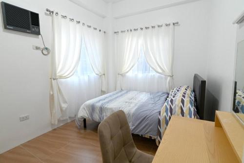 Baksanにある1 Cozy Bedroom Condo Unit-Apple One Banawa Cebuのベッドルーム1室(白いカーテンとテーブル付きのベッド1台付)