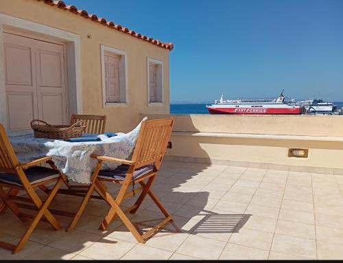 a patio with a table and chairs and a boat at Sophisticated Central House Tinos in Tinos