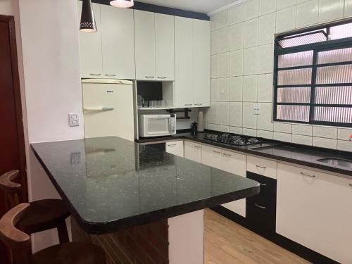 a kitchen with white appliances and a black counter top at Panamá 90 - 22 in Poços de Caldas