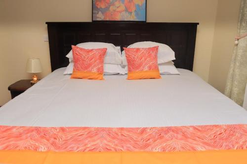 a bed with orange and white pillows on it at Royal Homes in Nairobi
