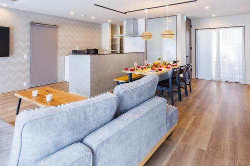 a living room with a blue couch and a table at 最大12名OK 駐車3台無料自然豊かな名護エリアの広々一棟貸し Marama Ryukyu 琉球 in Nago