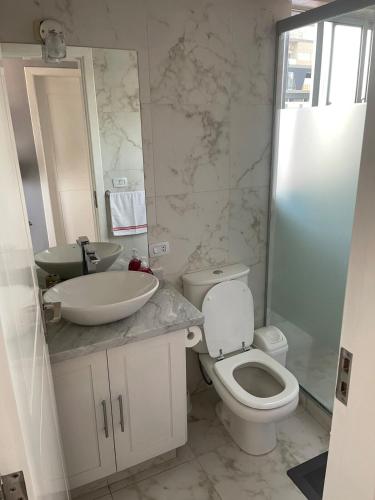 a bathroom with a sink and a toilet and a mirror at Exclusivo Departamento en Edificio Alessandria in Cochabamba