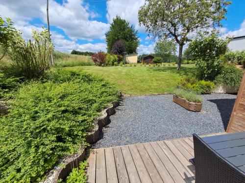 a garden with a wooden deck and a yard at Au Tchesseu in Neufchâteau