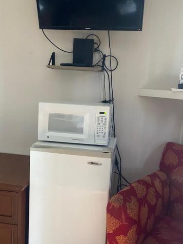 a microwave on top of a refrigerator with a chair at Barberry Court Motel &Cabins in Lake George
