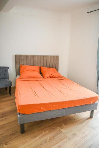 a bed in a room with an orange comforter at T3 au pied des plages in Cassis
