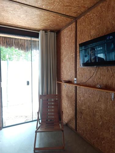 a room with a tv on the wall and a wooden chair at Nomads Village, Macapa in Luis Correia
