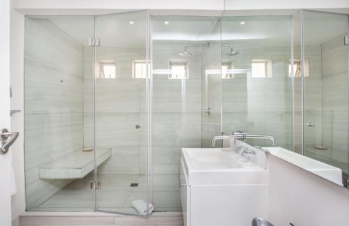 a white bathroom with a shower and a sink at Far Horizons Camps Bay in Cape Town
