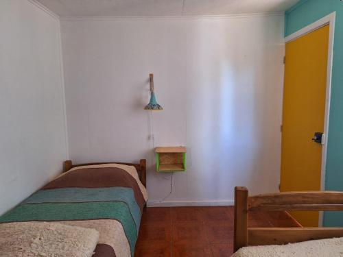 a room with two beds and a yellow door at Casona Diabla in San Fabián de Alico