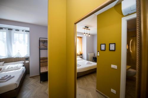 a yellow room with two beds and a mirror at Show MI Rooms Milano - San Siro Stadio - Ippodromo - Rho Fiera in Milan
