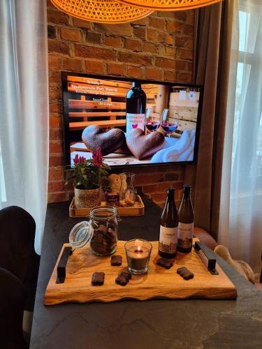 a table with a bottle of wine and a television at Apartament Przy Murach in Toruń