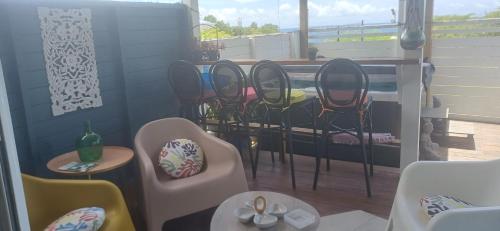 a group of chairs and tables on a balcony at Gîtes Capra Pomme Surette piscine et spa in Bouillante