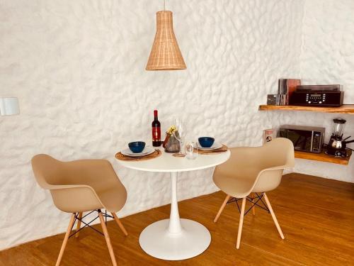 una mesa blanca con 2 sillas y una botella de vino en Greece house blue, en Paty do Alferes