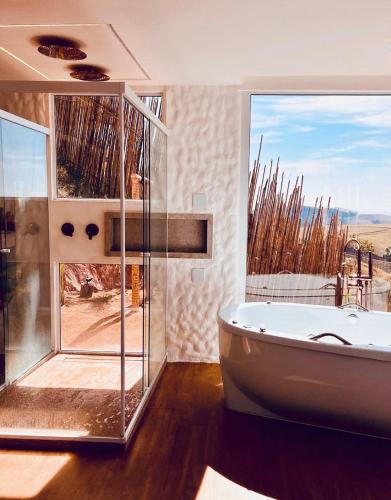 a bathroom with a tub and a large window at Cabana Greece house blue in Paty do Alferes