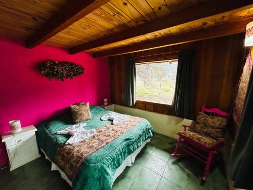 a bedroom with a bed and a pink wall at Complejo Peuma Hue in Lago Puelo