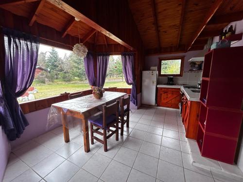 a kitchen with a table and purple curtains at Complejo Peuma Hue in Lago Puelo